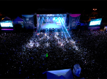 Grande foule devant une scène de spectacle extérieure la nuit à la Fête du Lac des Nations.