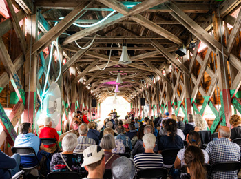 Foule assise dans une grange aménagée pour un spectacle.