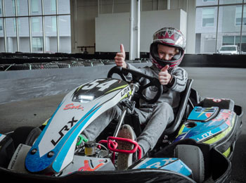 Jeune garçon dans un kart sur une piste de karting.