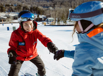 Monitrice tout sourire avec un élève sur les pistes.