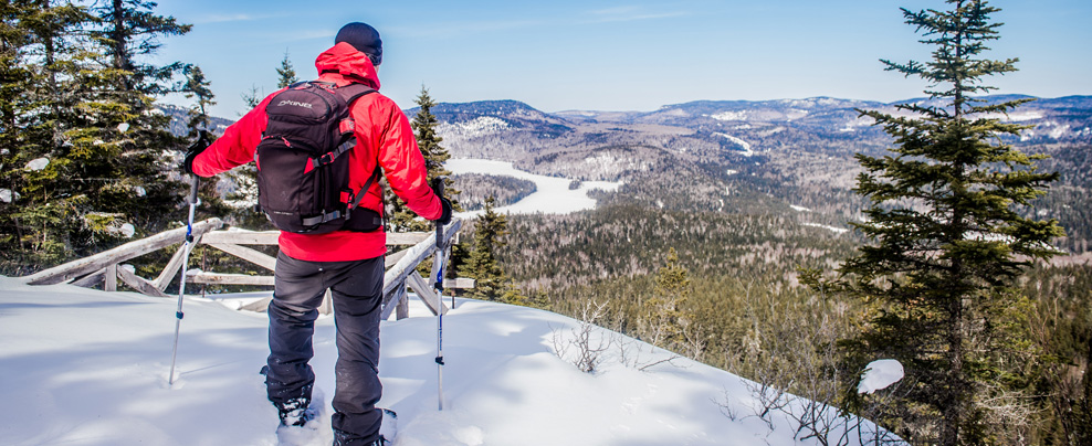 Raquetteur qui admire la vue au sommet du mont Brassard enneigé.