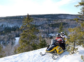 Deux personnes en motoneige devant les montagnes de la Mauricie