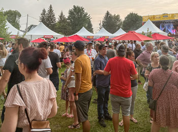 Foule en petits groupes autour de kiosques près du bord de l'eau.