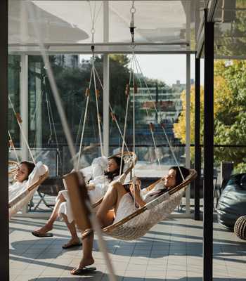 3 jeunes femmes sur la terrasse du spa dans des chaises-balançoires suspendues.