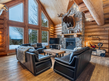 Intérieur d'un chalet luxueux avec foyer et fenêtre panoramique.