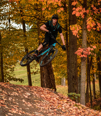 Cycliste de montagne qui fait un saut dans un décor automnal.