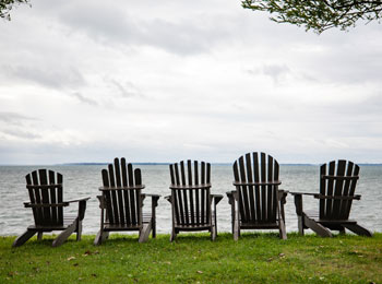Cinq chaises Adirondack au bord de l'eau.