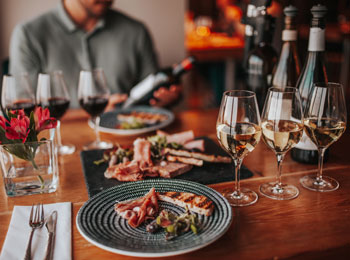 Table de dégustation avec assiette et plusieurs verres de vin.