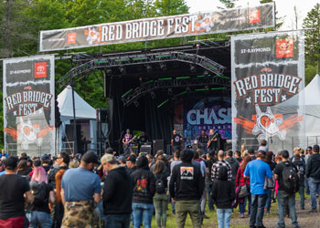 Foule devant une scène de festival en journée.