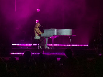 Charlotte Cardin au piano sur scène en soirée.