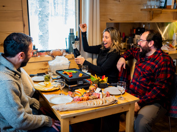 Deux couples attablés pour savourer une raclette et une bouteille de vin