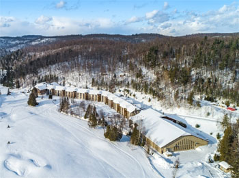 Vue aérienne de l’hôtel, entouré d’étendues enneigées et d’arbres dénués de leur feuillage.