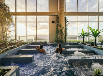 Deux filles dans les bains du Noah Spa qui regardent le fleuve par la baie vitrée.