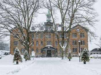 Devanture de l'Hôtel Montfort, un bâtiment d'allure historique de 4 étages, sous la neige.