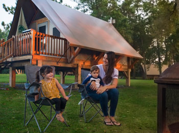 Mère et ses deux enfants au bord du feu de camp devant un prêt-à-camper
