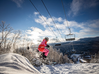 Skieuse qui fait un saut en-dessous de la remontée mécanique.