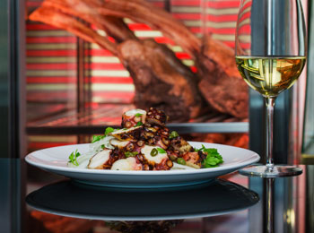 Assiette de fruits de mer soigneusement apprêtés, servie avec un verre de vin blanc.