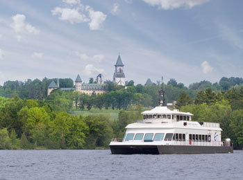 Navire de croisière sur un lac, avec une abbaye sur la rive en arrière-plan.