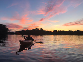 Personne en kayak sur la rivière au crépuscule.