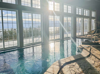 Piscine intérieure dans un spa à côté de baies vitrées.