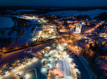 Village de pêche sur glace illuminé vu de haut dans la nuit.