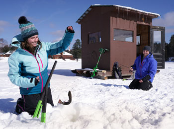 Couple en train de faire de la pêche sur glace par une journée ensoleillée.