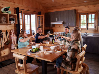 Groupe de convives autour d'une table à l'intérieur d'un chalet en bois.