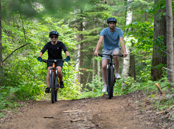 Deux personnes qui font du fatbike dans la forêt.