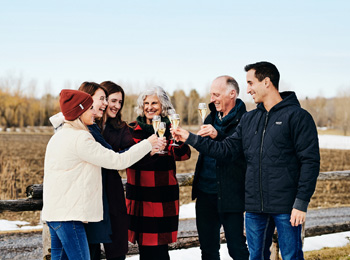 6 personnes heureuses à l'extérieur dans un vignoble l'hiver qui trinkent leurs verres de vin.