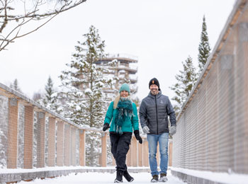 Couple souriant sur une promenage en bois enneigée.