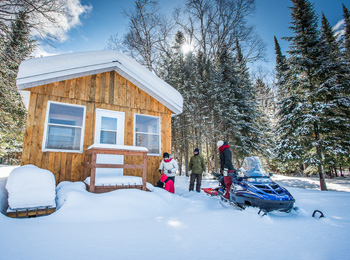 Chalet en hiver avec motoneigiste