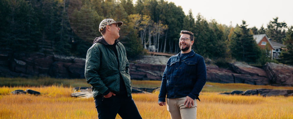 Deux hommes se sourient durant une activité en nature. 