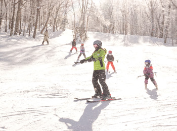 Moniteur de ski avec apprentis skieurs et skieuses derrière lui.
