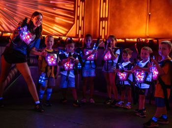 Monitrice avec sept jeunes enfants vêtus de gilets illuminés.
