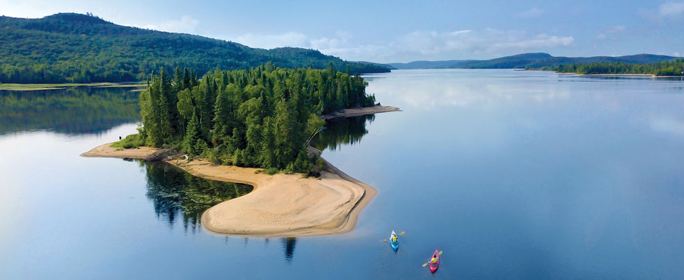 Vue aérienne d’une petite île avec plage au milieu d’un grand lac.