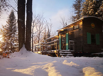 Mini-chalet dans un paysage enneigé sous une luminosité naturelle dorée.