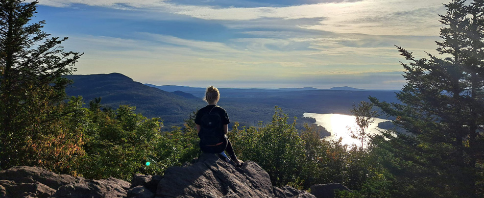 Femme au sommet d’une montage qui admire le paysage.